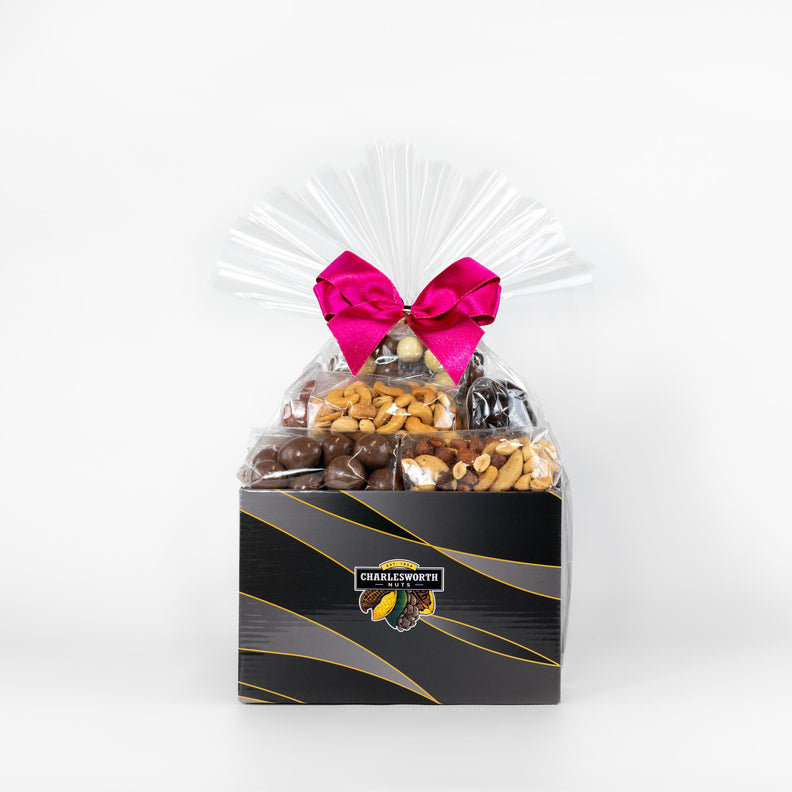 Mother's Day Gift Basket filled with nuts and chocolates wrapped in cellophane and tie with a pink bow.