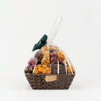 A wicker gift basket filled with assorted packaged snacks and nuts, wrapped in clear cellophane and tied with a dark green ribbon.
