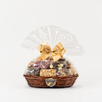"Christmas gift hamper with a gold bow and the base filled with chocolates, salted and sweet nuts."