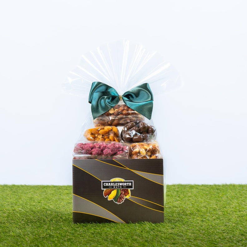 A gourmet snack Father's Day gift box from Charlsworth Nuts, filled with assorted dried fruits, chocolates, and nuts, wrapped in clear cellophane with a large green bow. 